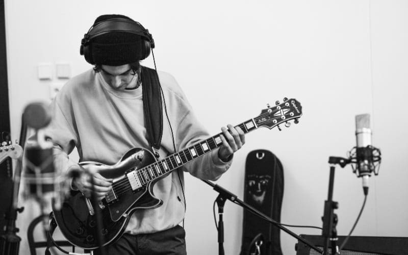 Man recording guitar with headphones Мusic Gateway