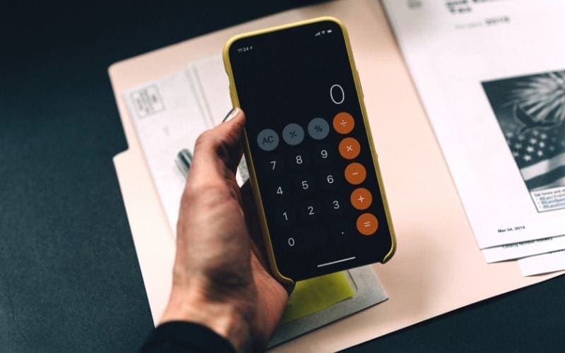person holding phone calculator to budget for the best recording studios in London