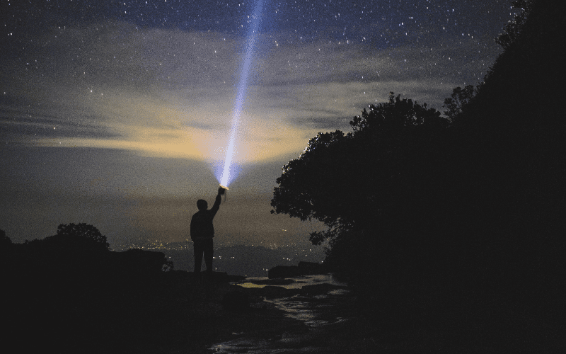 Man holding a searchlight to the sky