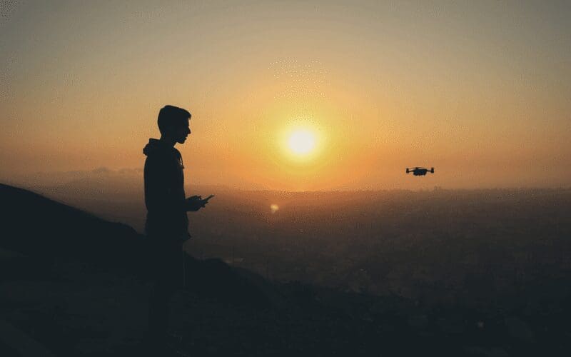 silhouette shot of man and drone golden hour