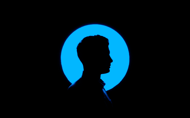 Silhouette of man in front of blue circle.