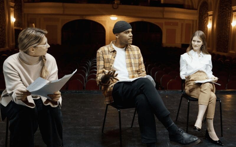 Three people discussing a script.
