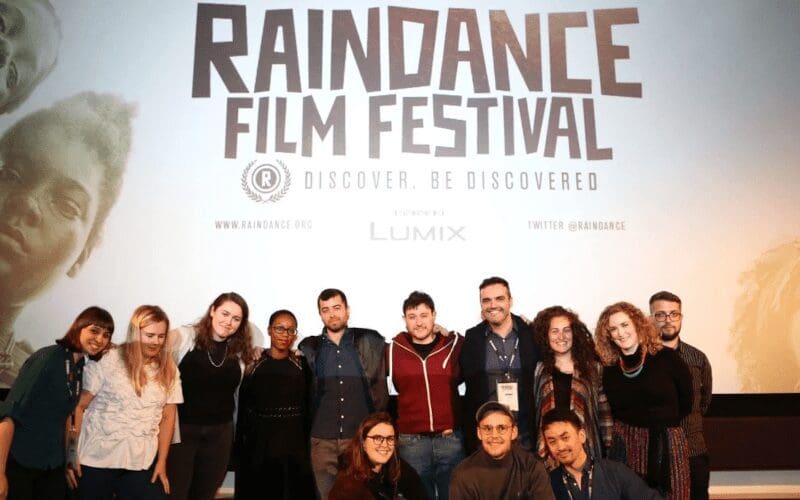 People standing in front of a Raindance film festival banner.