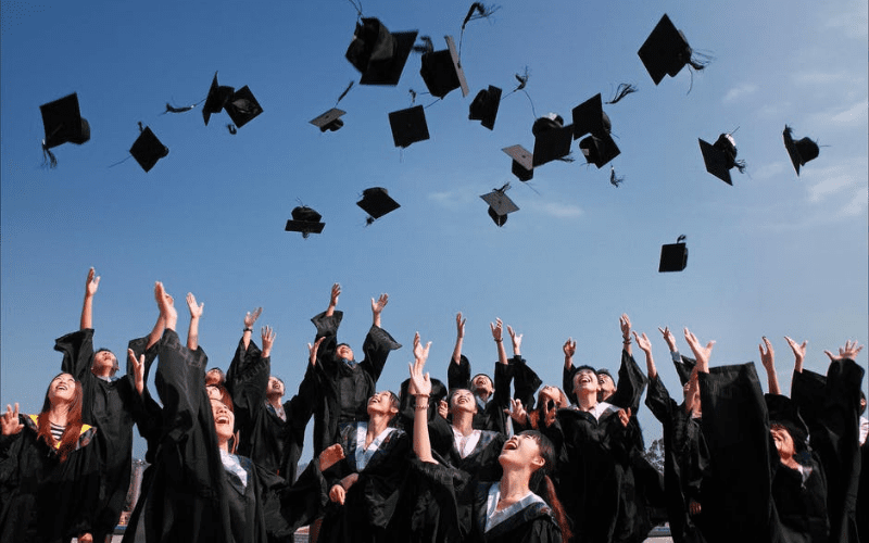 graduates throwing cap into the air