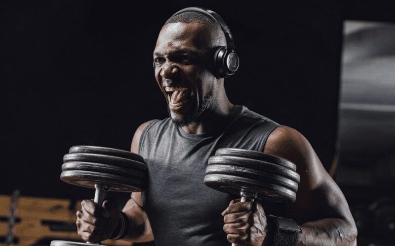man listening to music lifting dumbells in the gym