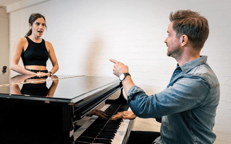 A vocal coach trains a background singer