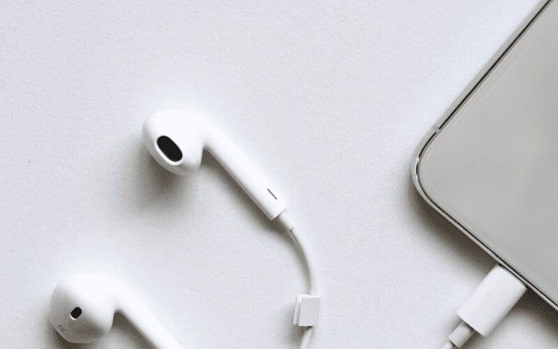 White Apple headphones next to a laptop