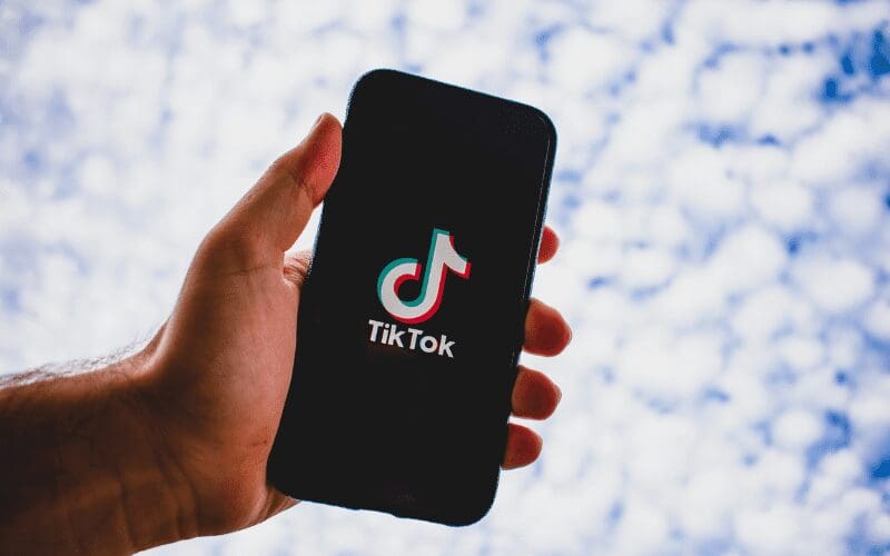 A hand holding a phone with the TikTok logo on screen.