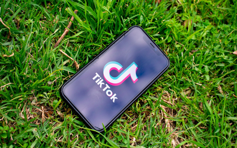 A phone on some grass displaying the TikTok Logo