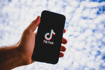 A hand holding a phone which displays the TikTok Logo