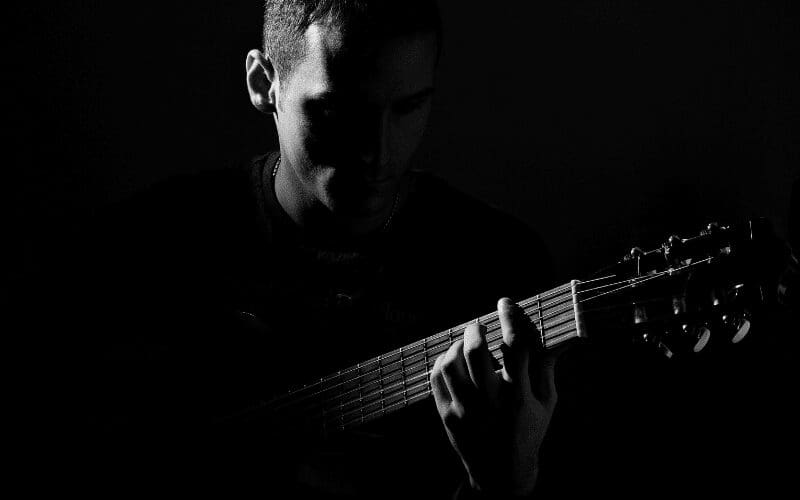 a black and white photo showing a person playing guitar