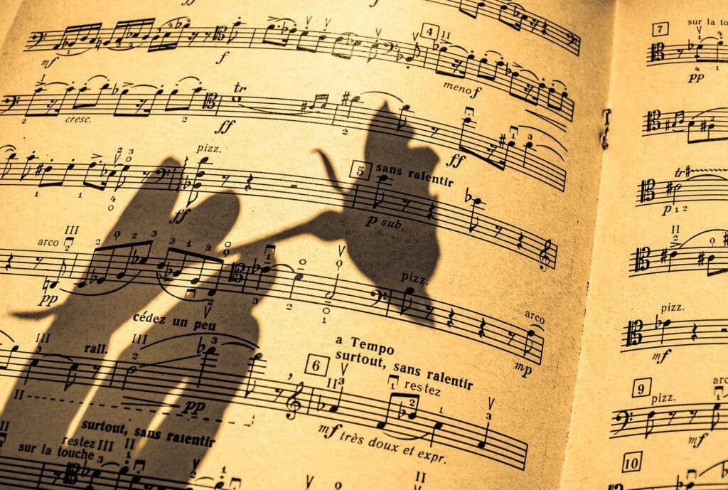 Shadow of a hand holding a rose over sheet music